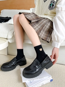 Close-up of black cotton socks with gold bear embroidery paired with chunky loafers