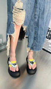 Detail of platform flip-flop with fluorescent yellow strap and silver metal triangle