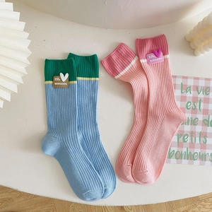 Detail of color-block crew socks with heart patch and ribbed cotton texture
