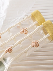 Macro shot of breathable mesh socks with delicate orange floral embroidery and yellow ribbing