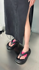 Close-up of black platform flip-flops with pink lining on feet with denim skirt