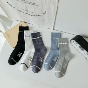 Flat lay of five pairs of ribbed mid-calf socks in various colors on a white table