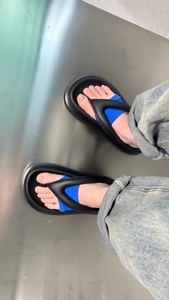 Close-up of black platform flip flops with blue fabric lining on metallic floor