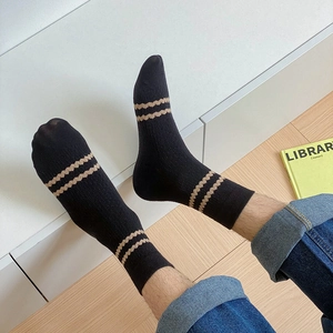 Macro detail of mid-calf cotton socks with khaki wave stripes on black ribbed knit fabric