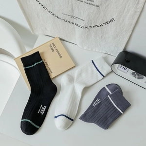 Flat lay of ribbed crew socks in black, grey and white with minimalist stripe detail