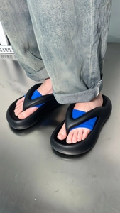 Close-up of black platform flip-flops with blue fabric accents worn with blue jeans