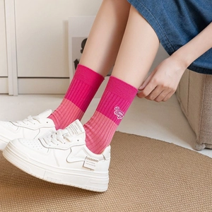 Pink rib-knit cotton mid-calf socks with Brave Beauty text paired with white sneakers