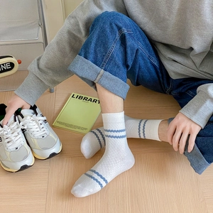 Close-up of white mid-calf cotton socks with blue wavy stripes on casual sneakers