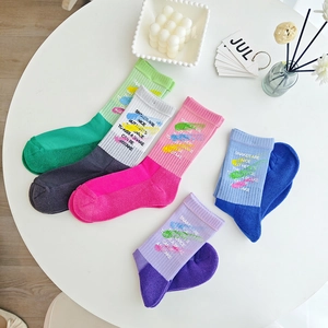 Flat lay of five pairs colorful mid-calf socks with playful graffiti and text on white table