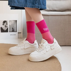 Close-up of pink crew socks with embroidered letters and white platform sneakers