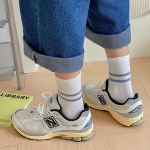Close-up of retro gray mesh sneakers and striped cotton socks on wooden floor