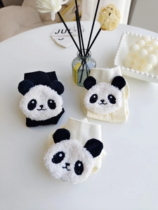Detail of cute 3D plush panda patch on cotton knitted socks in black and cream beige