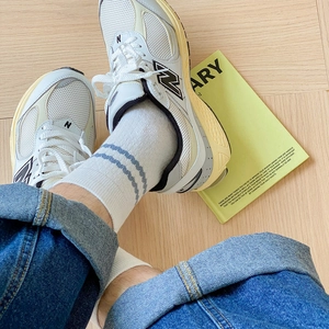 Close-up of retro off-white mesh and leather sneakers styled with white cotton socks