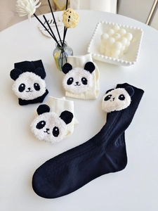 Detail of knit panda socks in black and cream featuring 3D plush doll decorations