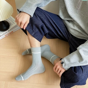 Close-up of light gray ribbed cotton mid-calf socks with white stripes on a wooden floor