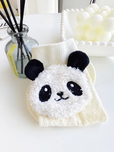 Macro detail of creamy white ribbed cotton sock featuring a plush 3D panda doll accessory