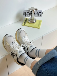 Close-up of white 2002R sneakers with black N logo and striped crew socks for men