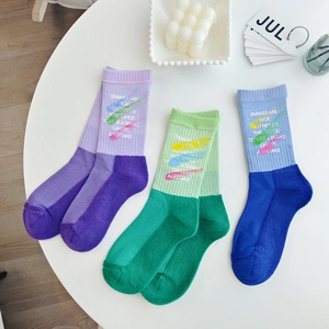 Three pairs of mid-calf cotton socks in contrasting colors with playful graffiti text