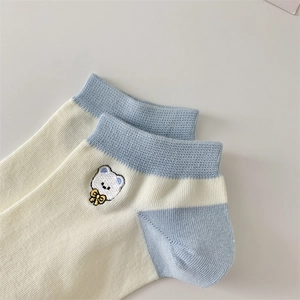 Detail of cotton ankle sock featuring a blue bear embroidery and yellow bow accent