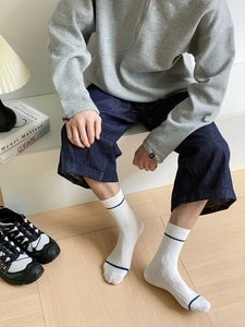 Detail view of white ribbed cotton mid-calf socks with blue stripes on wooden floor