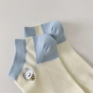Close-up of blue and cream cotton socks featuring detailed white bear embroidery decoration