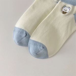 Close-up of cotton socks with blue toe and detailed white bear embroidery decoration