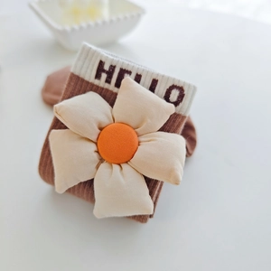 Détail de chaussettes en tricot marron avec fleur 3D et lettrage HELLO au revers
