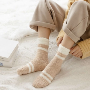 Close-up of cozy thick coral fleece striped socks on white textured blanket