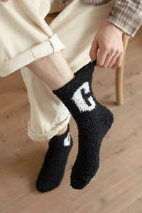 Detailed macro view of black coral fleece winter sock featuring a white letter G knit design