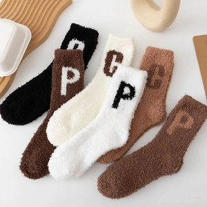 Flat lay of warm coral fleece socks with knit letters in earthy neutral tones