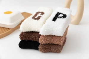 Close-up of thick coral fleece mid-calf socks with letter embroidery in earthy tones