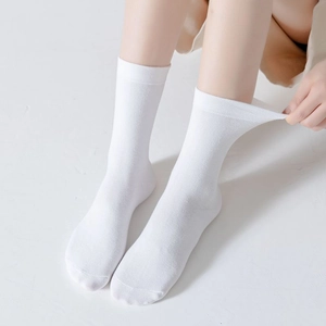 Detail of white cotton mid-calf socks showing ribbed cuffs and elastic texture on a model
