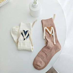 Detailed macro view of beige and coffee ribbed cotton socks with leather heart patches