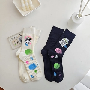 Detail of knit socks featuring colorful paint splatter patterns and smile face patch labels