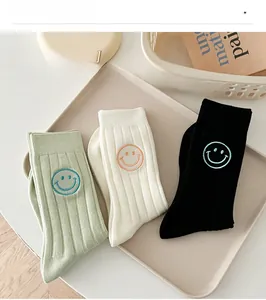 Three pairs of ribbed cotton socks in green, white, and black with smiley face embroidery