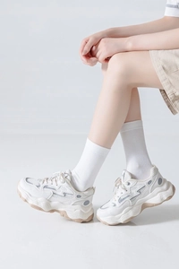 Close-up of off-white mid-calf cotton socks worn with stylish chunky sneakers