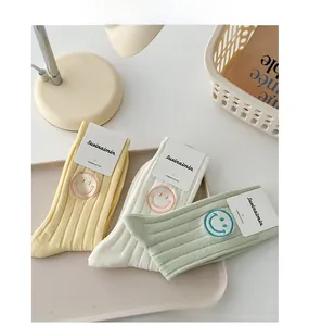 Detail of three combed cotton mid-tube socks with vertical ribbed texture and smile embroidery