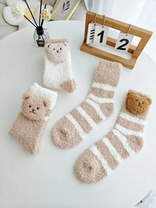Détail de chaussettes en polaire corail avec oreilles d'ours 3D et peluche rayée chaude