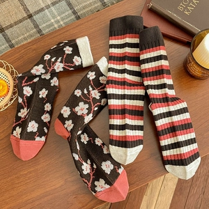Detail of vintage knit mid-calf socks with floral and striped patterns on wood table
