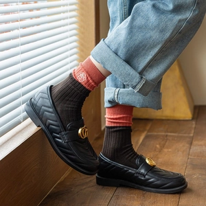 Close-up of retro knit socks with rose embroidery paired with quilted leather loafers
