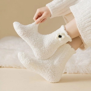 Detail of white thick coral fleece socks with 3D flower decoration and plush texture