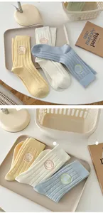 Detail of three-pack cotton socks featuring striped texture and smiling face embroidery