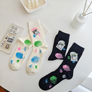 Detail of mid-calf socks with colorful spray paint dots and Stay Smile smiley face patch