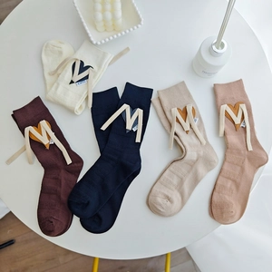 Flat lay of five mid-calf knit socks with heart patches and M-shaped lace-up detailing