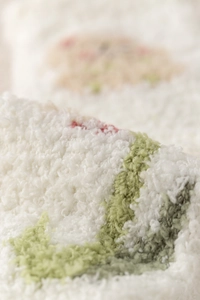 Macro detail of soft white coral fleece fabric with pink tulip embroidery on warm socks