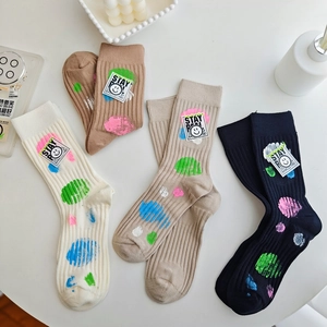 Detail of ribbed knit cotton mid-calf socks with colorful dots and smiley face patches