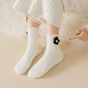 Close-up of fuzzy white coral fleece socks featuring cute black and white floral embroidery