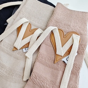 Detail of knit socks featuring heart leather patches and herringbone drawstring accents