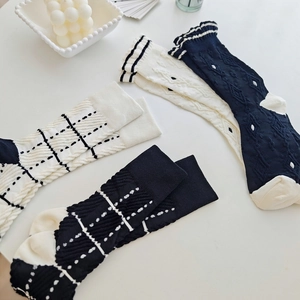 Detailed knit patterns of checkered and ribbed crew socks in minimalist white and black colors