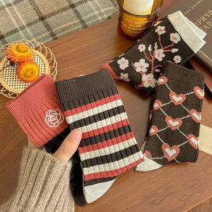 Retro style mid-calf knit socks set with floral and stripe patterns on wood background